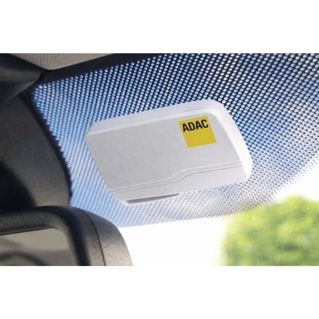 Eine ADAC Mautbox in der Farbe weiß, welche im Auto an der Windschutzscheibe angebracht ist.