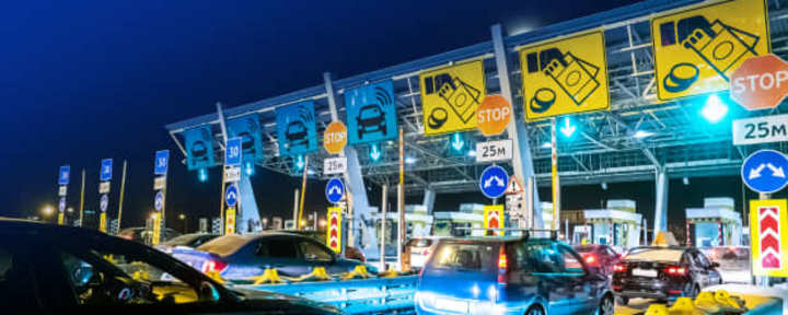 Fahrzeuge an einer Mautstation mit automatischer Mauterfassung bei Nacht.