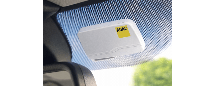 Eine ADAC Mautbox in der Farbe weiß, welche im Auto an der Windschutzscheibe angebracht ist.