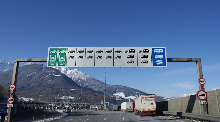 Beschilderung an Mautstation in den Alpen mit Fahrzeugklassen und Symbolen zur digitalen Maut und Streckenmaut