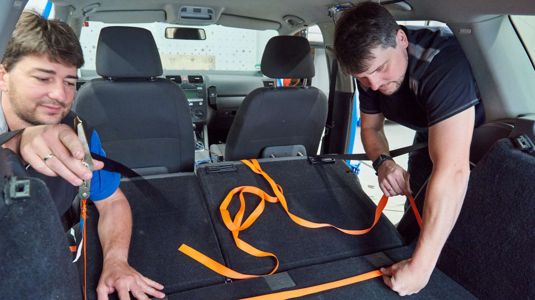 Mitarbeiter befestigen Spanngurte in Vorbereitung für den Crashtest Gepäcksicherung