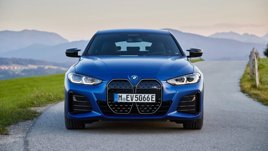 Der neue blaue BMW i40 M50 parkend von vorne auf einer Landstrasse in den Bergen