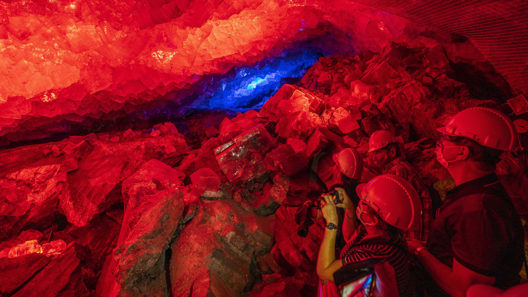 Zwei Menschen fotografieren rot angestrahltes Gestein in einem Bergwerk