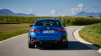 Der neue blaue BMW i40 M50 fahrend von hinten auf einer Landstrasse