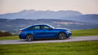 Der neue blaue BMW i40 M50 fahrend von der Seite in einer Berglandschaft