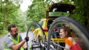 Ein Pannenhelfer des ADAC hilft einer Frau bei einer Fahrradpanne