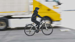 Fahrradfahrerin fährt neben LKW