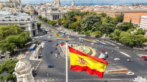 Spanische Flagge mit Plaza de Cibeles in Madrid im Hintergrund
