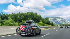 Auto mit Dachbox und Fahrrädern auf dem Fahrradträger auf der Autobahn