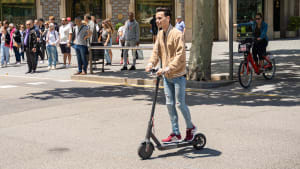 Mann fährt mit Elektro-Scooter auf einer Straße in Barcelona.