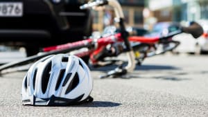 Nahaufnahme eines Fahrradhelms, der nach einem Autounfall auf der Straße in der Stadt neben einem Fahrrad auf den Asphalt gefallen ist