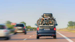Kleinbus mit Fahrradheckträger und Dachbox fährt auf der Autobahn