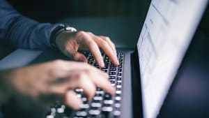 Close-Up von Männerhänden auf einer Tastatur am Laptop