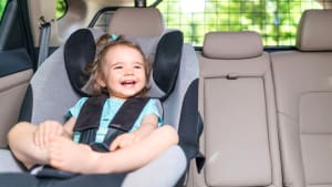 Baby sitzt im Kindersitz im Auto und lacht