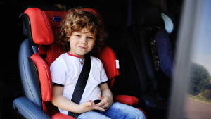 Junge sitzt angeschnallt im Kindersitz im Auto