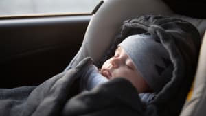 Baby schläft in einem Schlafsack in seinem Kindersitz