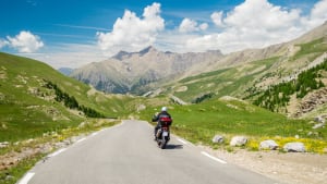 Ein Motorrad fährt auf einer Strasse durch einen Gebirgslandschaft
