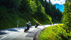 Motorradfahrer auf einer Straße durch einen Wald