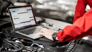 Mechaniker wertet Daten eines Autos mit Laptop aus