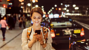 Junge Frau textet mit einem Uber-Fahrer abends in der Stadt