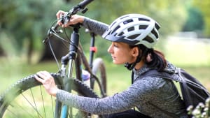 Eine Frau testet den Luftdruck in den Reifen ihres Fahrrads