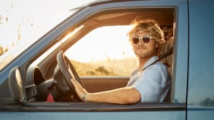 Mann mit Sonnenbrille fährt Auto