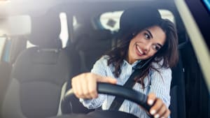 Eine Frau telefoniert während des Autofahrens, sie hat das handy zwischen Schulter und Kopf geklemmt
