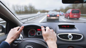 Hände am Steuer eines Autos während dem Überholen auf der Autobahn