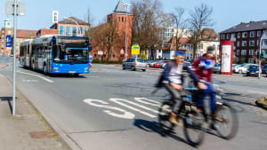 Ein Bus, Auto und zwei Fahrradfahrer auf einer Straße in Münster