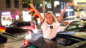 Junge Frau bei einem Fußball Autokorso mit Deutschland Blumenkranz in der Hand