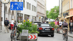 Eine Spielstraße mit Autos, Radfahrern und Fußgängern