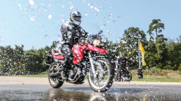 Rotes Motorrad fährt auf nasser Fahrbahn beim ADAC Fahrsicherheitstraining
