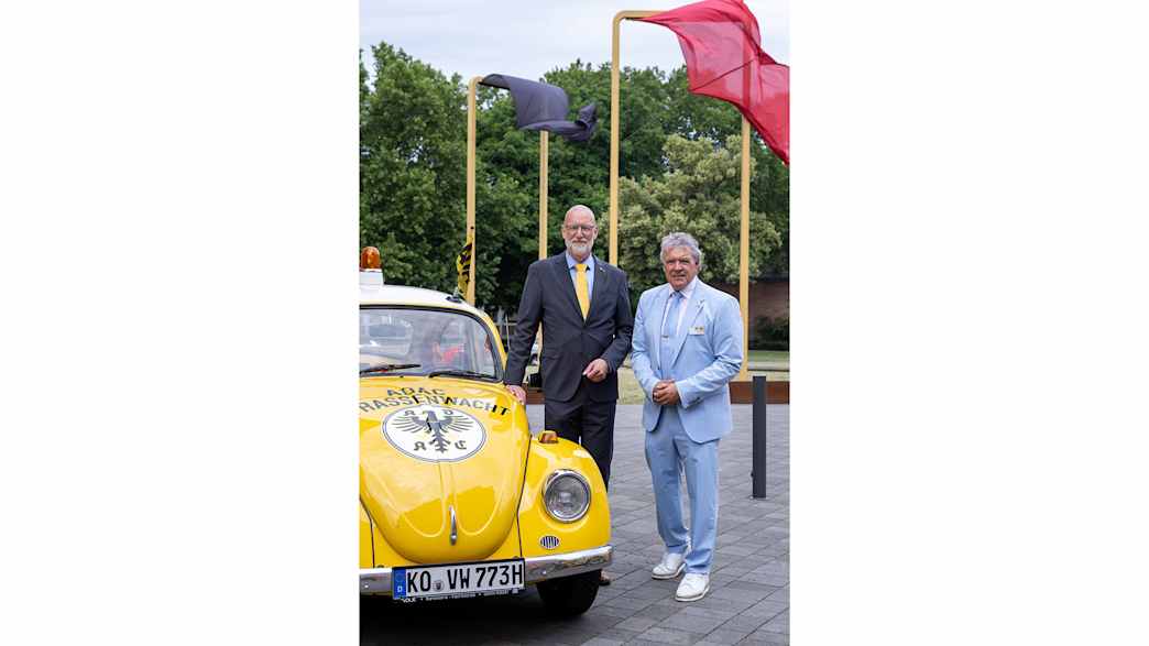 Rudi Speich und ein weiterer Mann neben dem historischen VW Käfer der Straßenwacht.