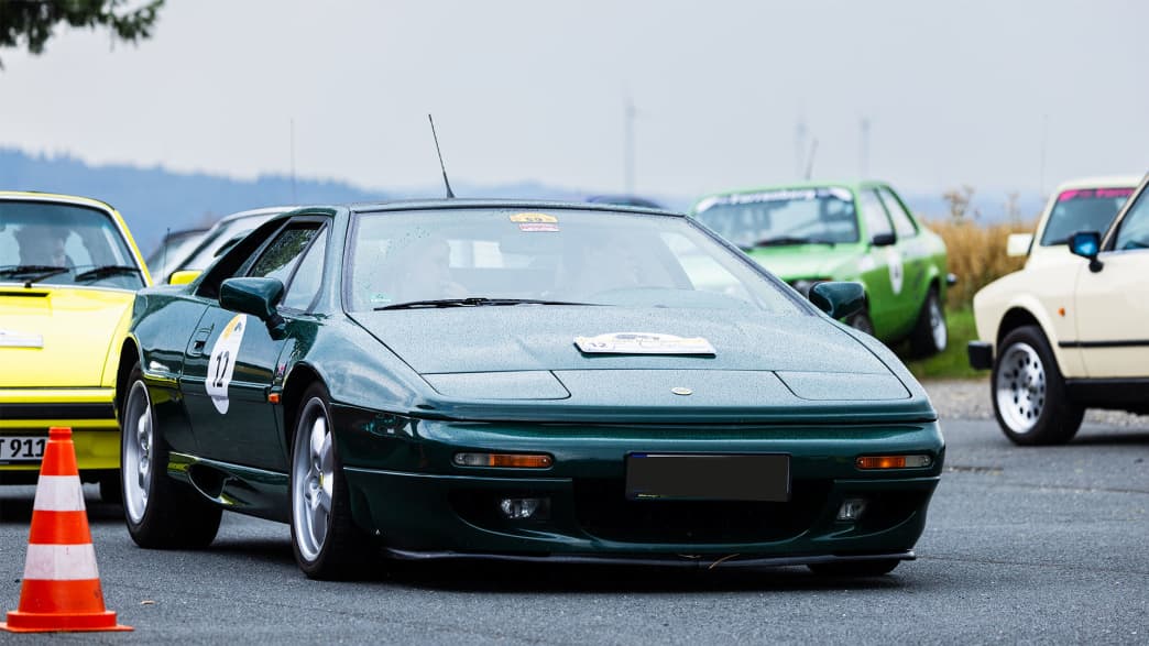 Lotus Esprit S4, Baujahr 1993: Ein dunkelgrüner Lotus Esprit, der für seine aerodynamische Form und leistungsstarke Performance bekannt ist, fährt durch eine klassische Autoshow.