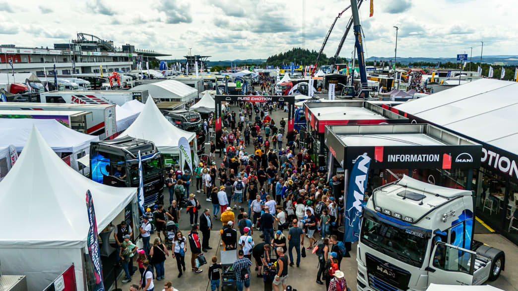 Belebtes Outdoor-Festival mit verschiedenen Ständen und ausgestellten Trucks, das eine lebhafte und geschäftige Atmosphäre zeigt.