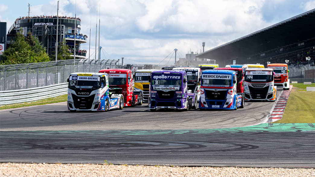 Nahaufnahme von Renntrucks, die eine Kurve auf einer Rennstrecke navigieren, und die Aufregung des Events zeigen.