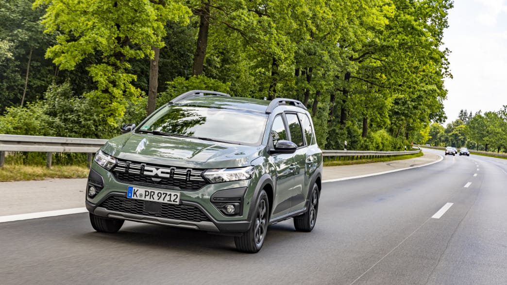 Grüner LPG Dacia Jogger fährt auf einer Straße neben einem Wald und wird mit LPG-Autogas betrieben