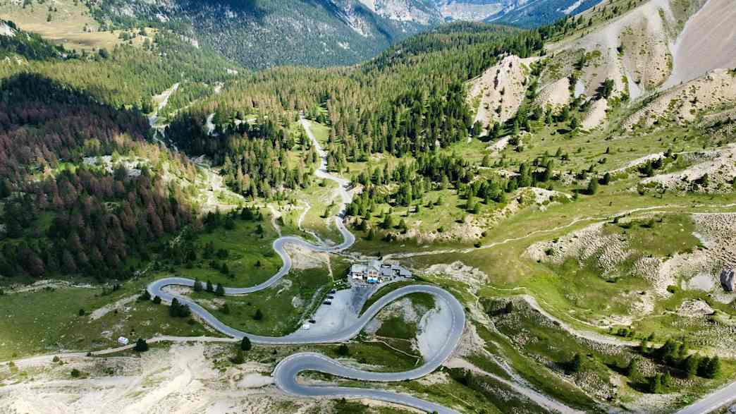 Motorräder fahren die Nordrampe des Col d'Izoard hinauf, umgeben von alpiner Landschaft.