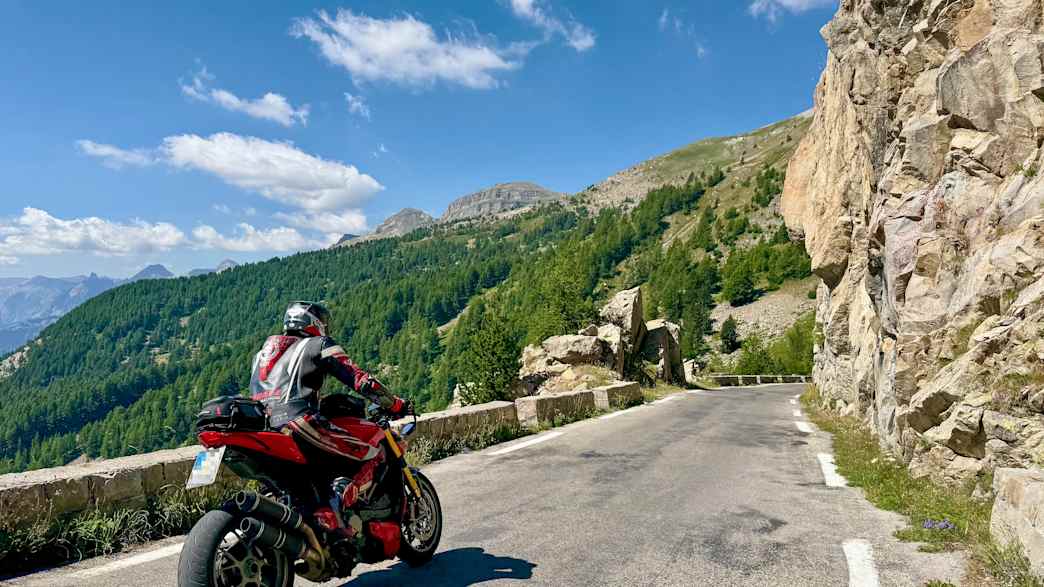 Ein Motorradfahrer fährt auf der kurvigen Südrampe des Col de la Cayolle durch die malerischen Täler der französischen Seealpen.