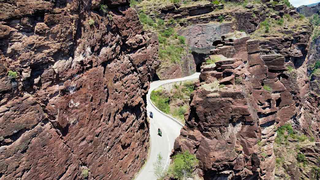 Luftaufnahme der Gorges de Daluis mit roten Felsen und einer kurvigen Straße, auf der Motorräder fahren.