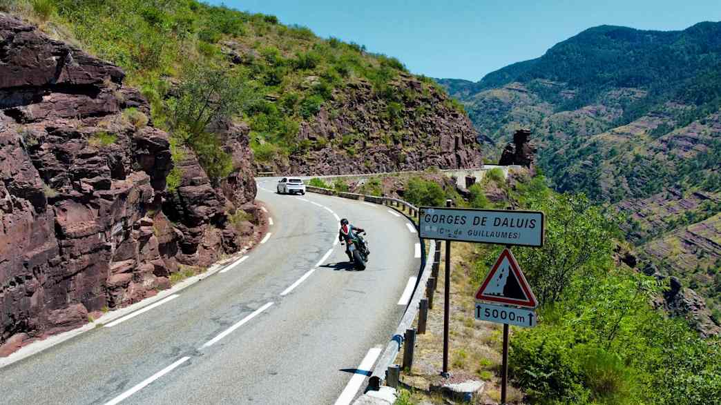 Ein Motorradfahrer passiert ein Straßenschild in den Gorges de Daluis in den französischen Seealpen