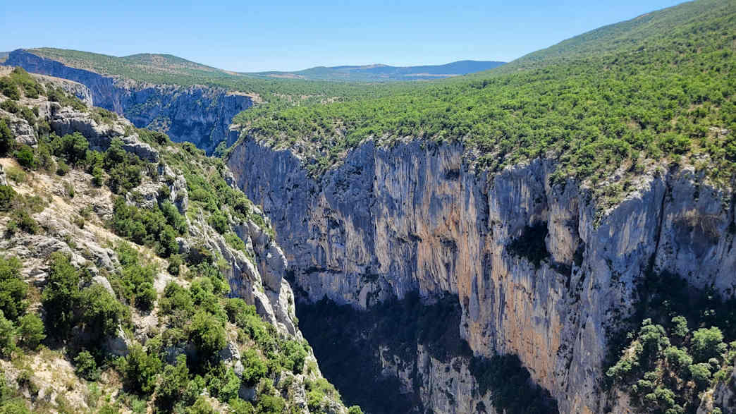 Felsklippen an den Gorges du Verdon mit Blick ins grüne Tal und bewachsenen Hängen.