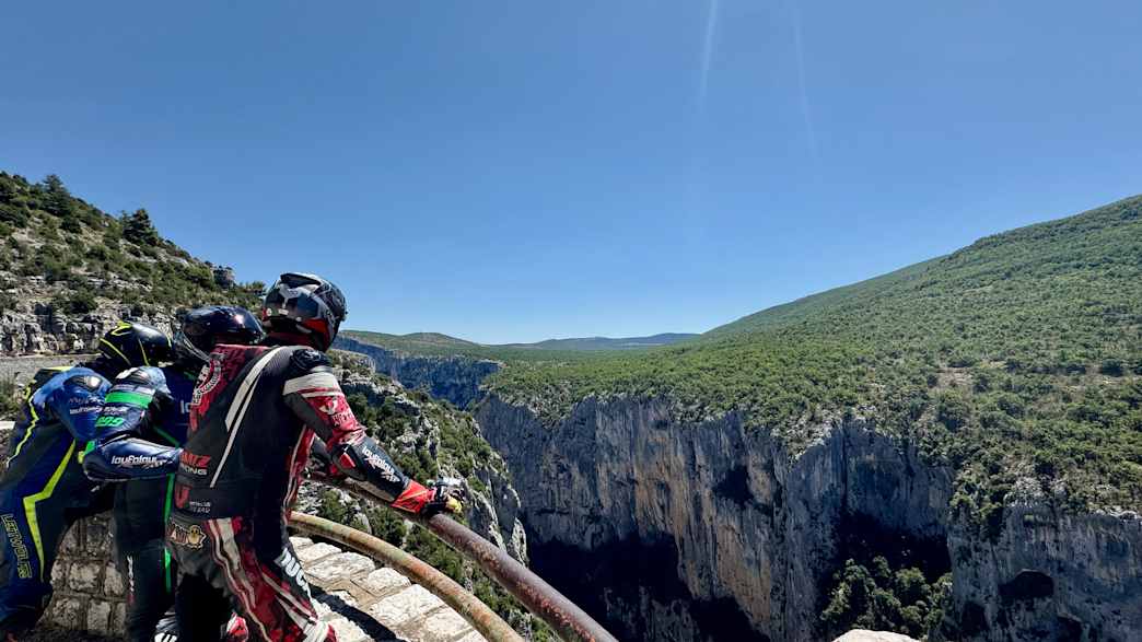 Motorradfahrer steht an einem Aussichtspunkt mit Blick auf die beeindruckende Schluchtlandschaft der Gorges du Verdon.