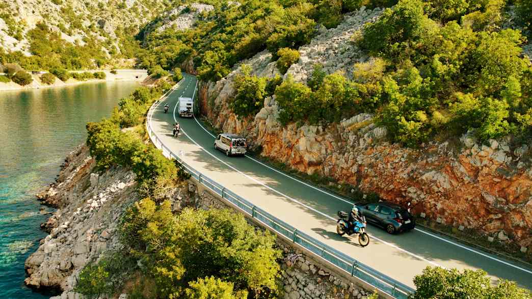 Motorradfahrt an der Küstenstraße in Kroatien mit Verkehr und Meeresblick.