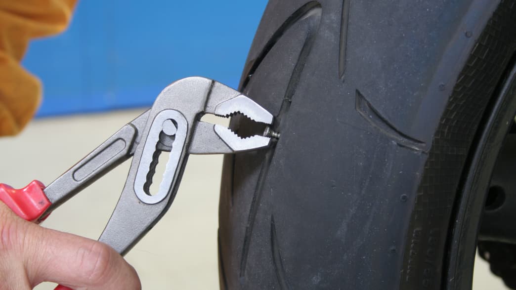 Schraube wird aus einem Motorradreifen entfernt