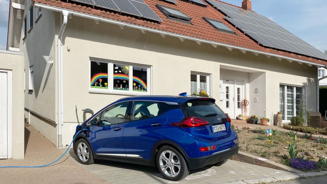 Ein blauer Opel Ampera-e läd an einem Privatgrundstück