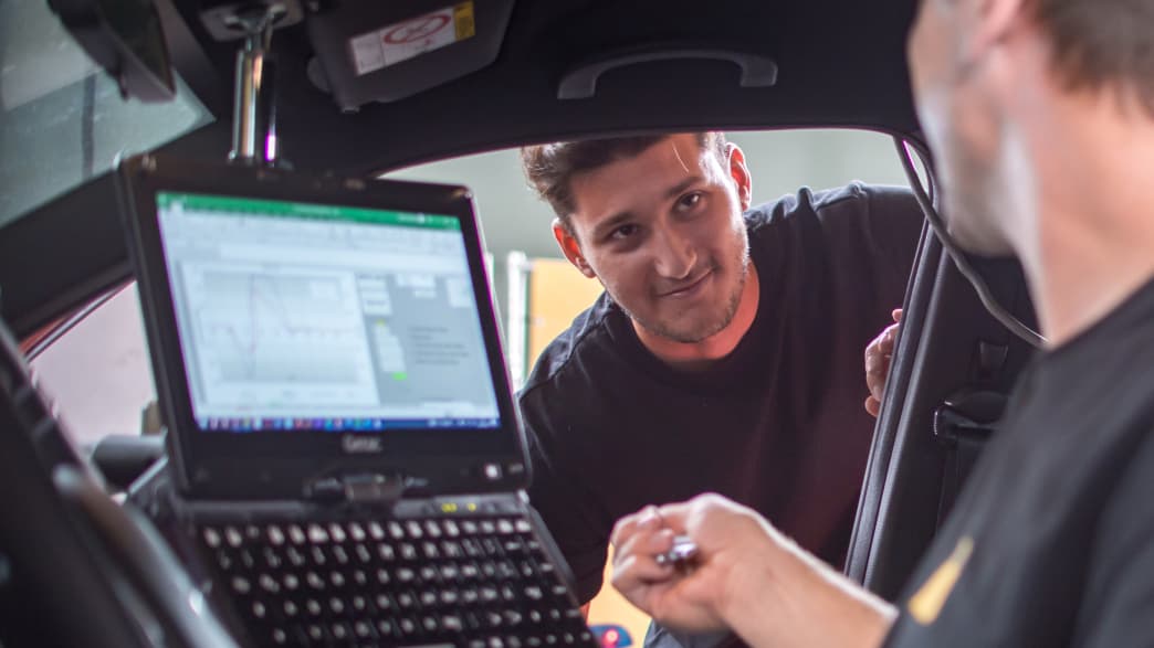 Zwei Männer mit einem Computer, testen ein Auto