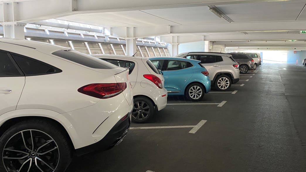 Ein blauer Renault Clio im Parkhaus zwischen lauter weißen Autos