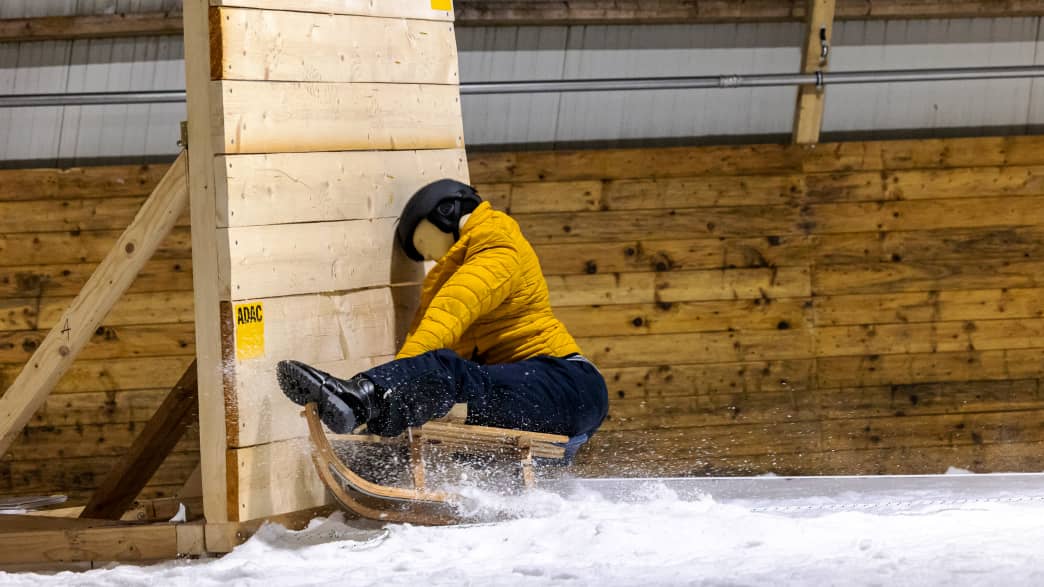 Ein Dummy mit Helm rast auf einem Schlitten gegen eine Wand beim ADAC Schlittencrashtest in der Skihalle in Bottrop