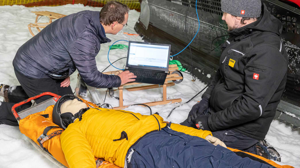 Zwei Techniker lesen die Daten eines Dummy nach dem ADAC Schlittencrashtest in der Skihalle in Bottrop